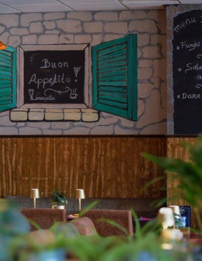 Sfeervol interieur van restaurant San Mario's in Zeewolde met muurschildering met turquoise luiken, krijtborden met menu’s en