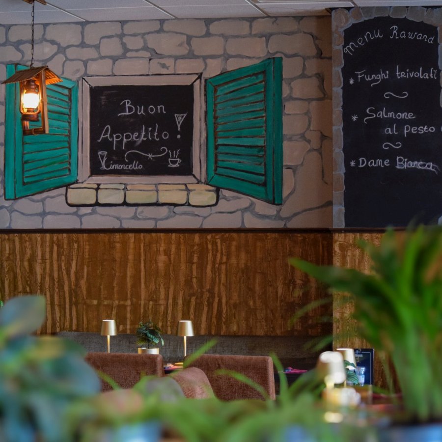 Buon appetito Atmospheric interior of restaurant San Mario's in Zeewolde featuring a mural with turquoise shutters, chalkboards with menus and