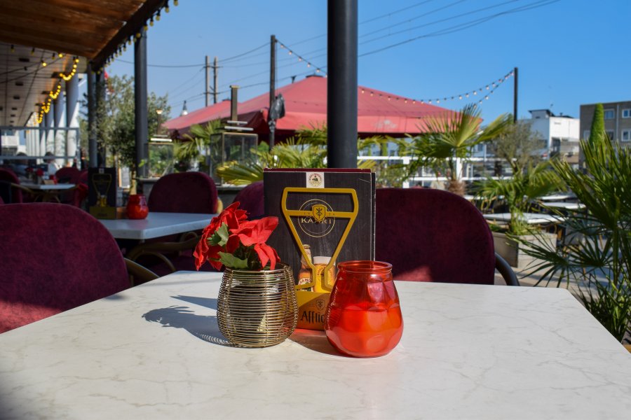 Terrace of Italian Restaurant San Mario's with a view of the quay and Aanloophaven of Zeewolde, with set tables, red accents, and an atmospheric outdoor seating area.